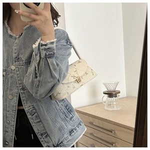 Chic cream woven underarm bag featuring delicate green floral embroidery and gold twist lock