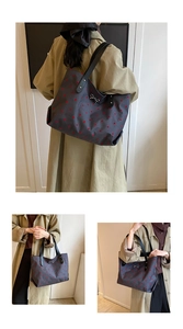 Detail of large grey tote bag with red polka dots, silver bow and black leather straps