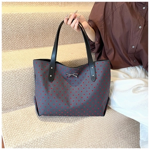 Detailed view of grey canvas tote bag with red heart patterns and silver bow buckle
