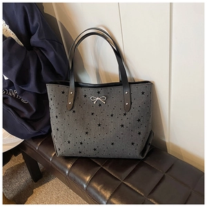 Close-up of grey tote bag with black star prints and silver metallic bow detail