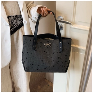 Detail of dark grey tote bag with black flocked stars and silver bow pendant