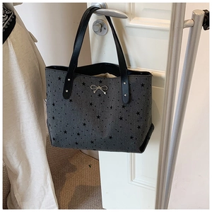 Detailed close-up of dark grey canvas tote with black stars and silver bow detail