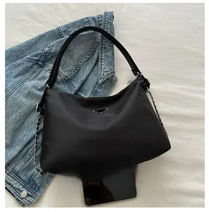Close-up of black nylon hobo bag featuring a metal triangle logo and chain detail