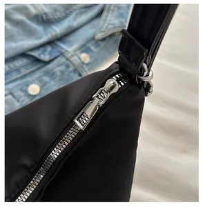Close-up of a smooth silver metal zipper on a black nylon shoulder tote bag