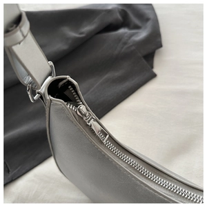 Macro detail of silver metal zipper and D-ring buckle on gray leather shoulder bag