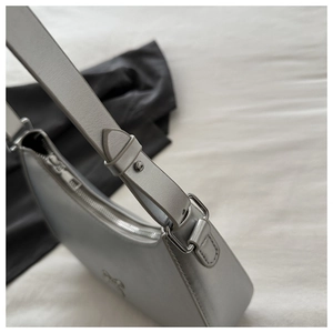 Detail view of silver grey shoulder bag with metallic bow buckle and leather strap