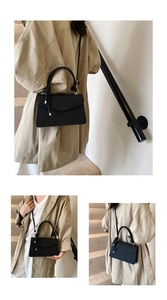 Close-up of black crossbody bag featuring a unique knotted handle and vertical texture