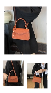 Detail of orange-brown pleated leather handbag with envelope flap and gold hardware