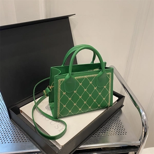 Green square handbag with heart embroidery and top handles on a premium gift box