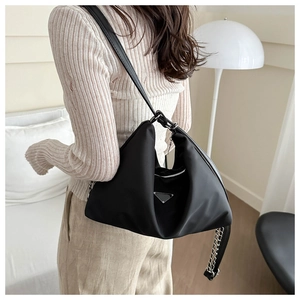 Detail of a black nylon hobo shoulder bag with metal logo and silver chain decoration