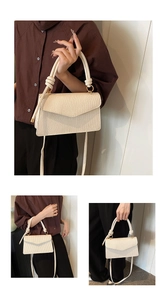 Detail of cream white textured handbag with knotted handles and gold metal hardware