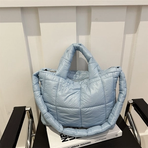 Quilted light blue puffer tote bag with wide straps on a chair in a minimalist setting