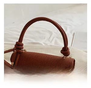 Close-up of the stylish red-brown handbag featuring a unique knotted round handle design
