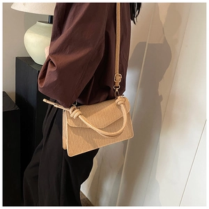 Detail of apricot pleated texture handbag with knotted handle and elegant flap design