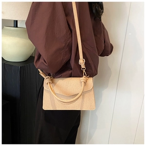 Detail of beige pleated texture handbag with gold metal buckle and adjustable strap