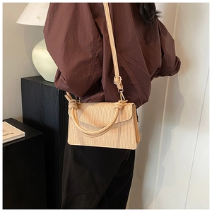Detail of cream pleated shoulder bag with knotted handle and elegant gold hardware