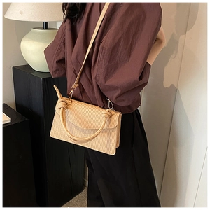 Detail of pleated apricot crossbody bag showing knotted handle and shoulder strap