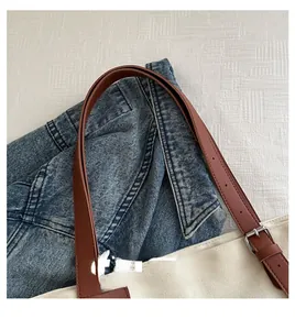 Detail of brown leather strap and silver buckle on off-white canvas tote bag