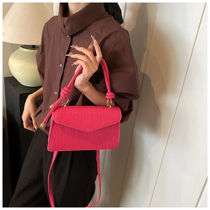 Close-up of fuchsia pleated leather handbag featuring a knotted handle and V-flap design