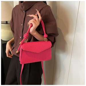 Close-up of rose red pleated texture handbag with knotted handle and gold metal hardware