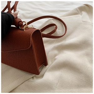 Detail of caramel brown crossbody bag with vertical pleated texture and gold ring hardware
