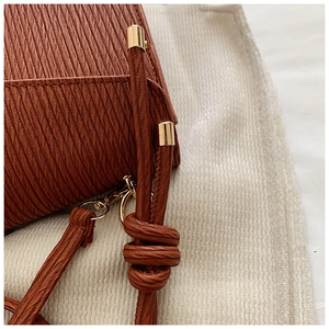 Detail of caramel textured leather handbag showing the knotted strap and gold hardware