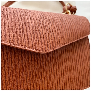 Detailed view of caramel wave pattern leather texture and fine stitching on handbag
