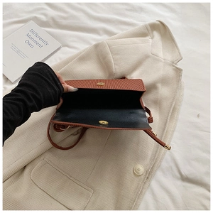 Detail of brown textured crossbody bag showing magnetic closure and interior compartment