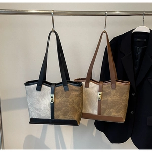 Detail of vintage canvas tote with leather trim and gold buckle on a metallic rack