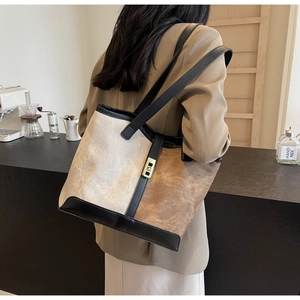 Detail of a large color-block tote bag with vintage brown and beige stitching and gold buckle
