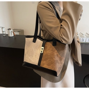 Detail of color-block tote bag with gold twist lock and textured fabric texture
