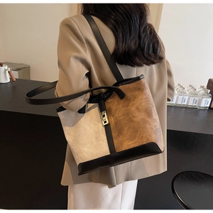 Detail of a large contrast stitch tote bag worn by a model in a minimalist setting