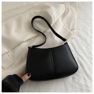 Détail du sac seau noir en cuir PU mat avec large bandoulière et boucle dorée chic
