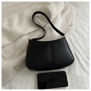 Détail d'un sac seau noir avec bandoulière large à côté d'un smartphone pour taille