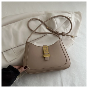 Detail of matte leather underarm bag featuring a vintage golden geometric metal clasp
