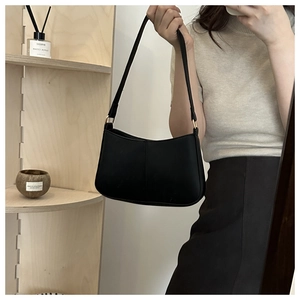Détail d'un sac à bandoulière minimaliste en similicuir noir avec boucle dorée élégante