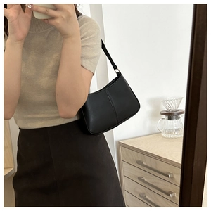 Gros plan d'un sac sous les aisselles noir minimaliste avec ferrures dorées et cuir