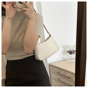 Sac seau en cuir blanc avec bandoulière large ajustable porté par un mannequin