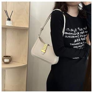 Detail of cream leather hobo bag featuring a decorative gold Greek key buckle and knot strap
