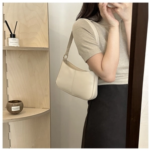 Selfie miroir montrant le sac baguette minimaliste crème porté à l'épaule dans un cadre moderne