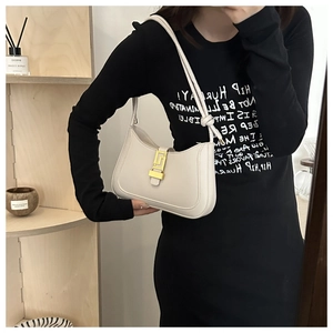 Close-up of beige minimalist underarm bag with gold geometric clasp on a wooden shelf
