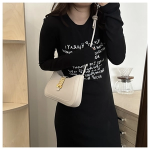 Détail d'un sac demi-lune en cuir beige avec une boucle géométrique dorée élégante