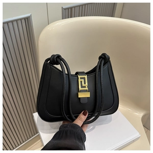 Detail of black crescent handbag with vintage golden geometric clasp and knotted leather handle