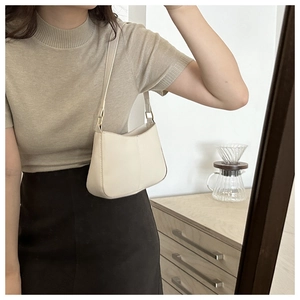 Détail d'un sac sous les bras en similicuir blanc crème avec texture lisse et garniture