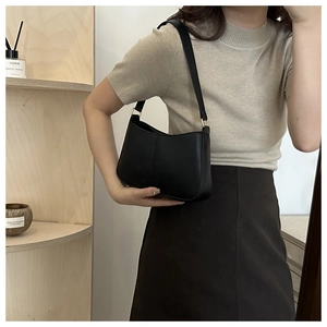 Détail du sac à bandoulière en cuir mat noir avec boucle dorée et couture verticale