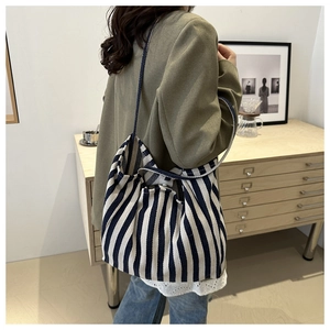 Detail of blue and white striped canvas tote bag with woven shoulder strap and magnetic snap