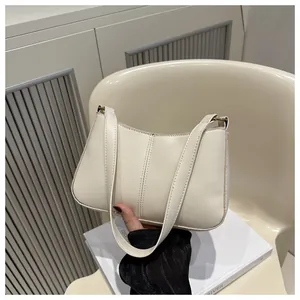 Détail d'un sac baguette crème élégant avec coutures verticales porté à la main