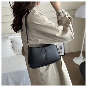Détail d'un sac sous le bras noir minimaliste avec couture verticale et boucle dorée chic