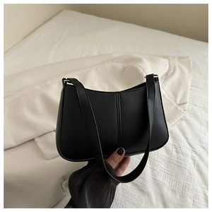 Gros plan du sac baguette en cuir noir avec deux bandoulières et boucles dorées chic