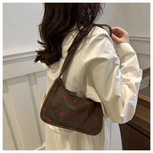 Détail du sac sous l'aisselle en velours côtelé marron foncé avec broderie fraise
